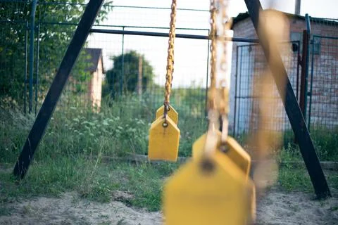 Yellow rubber swing on chains in the backyard Stock Photos