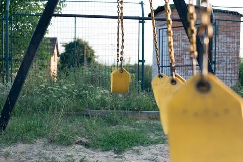 Yellow rubber swing on chains in the backyard Stock Photos