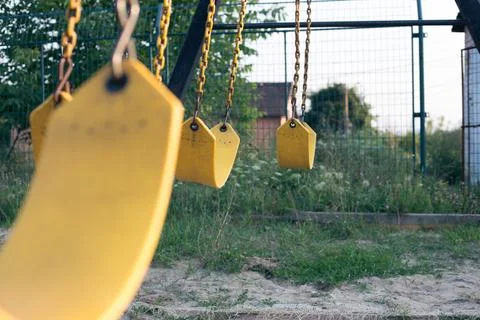 Yellow rubber swing on chains in the backyard Stock Photos