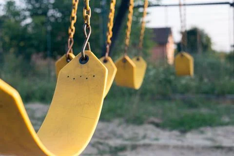 Yellow rubber swing on chains in the backyard Stock Photos