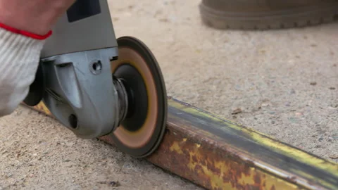 Yellow rusted square steel pipe is being cleaned with angle grinder and flap Stock Footage 272518657