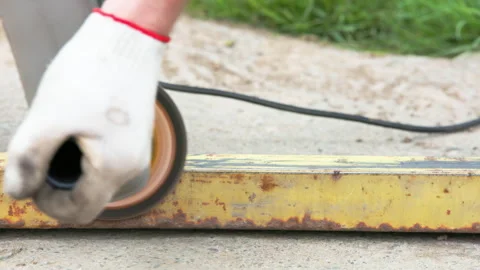 Yellow rusted square steel pipe is being cleaned with angle grinder and flap Stock Footage 273142864