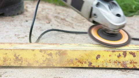 Yellow rusted square steel pipe is being cleaned with angle grinder and flap Stock Footage 273654149