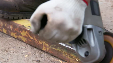 Yellow rusted square steel pipe is being cleaned with angle grinder and flap Stock Footage 273972390