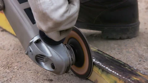 Yellow rusted square steel pipe is being cleaned with angle grinder and flap Stock Footage 274445030