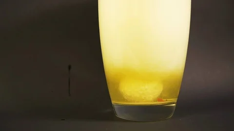 Yellow salt bath close up dissolves in vase of water in slowmotion with drilling Stock Footage 119033984
