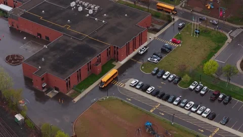 Yellow school bus arriving at brick building elementary school, dropping off stu Stock Footage 334697040
