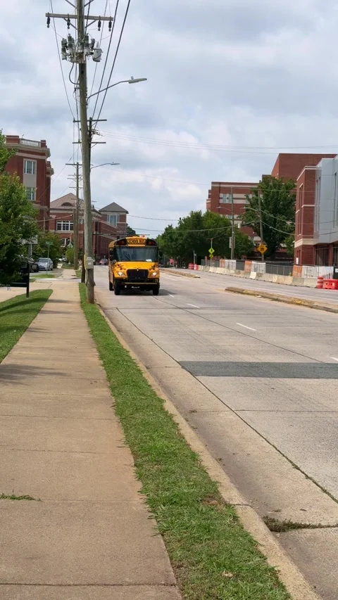 A yellow school bus drives down the street Stock Footage 337497635