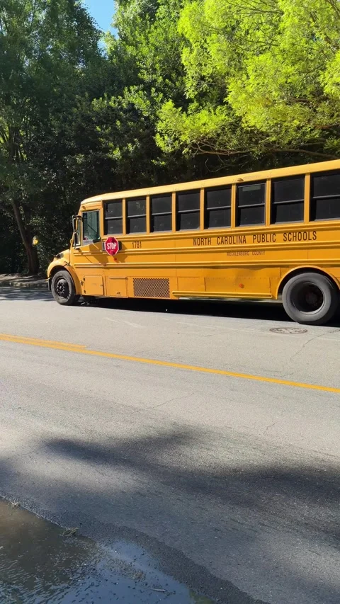 A yellow school bus drives down the street 스톡 동영상 337497665