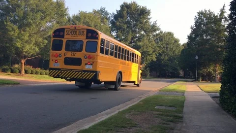 Yellow school bus driving through a neighborhood Stock Footage 94390641