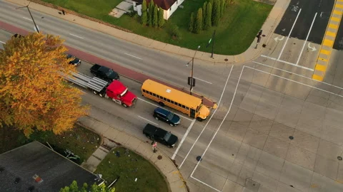 Yellow school bus with students inside making a left turn at an intersection Stock Footage 162816339