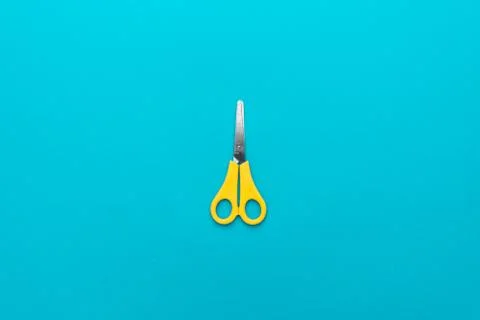 Yellow scissors on the blue background Stock Photos