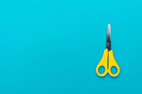 Yellow scissors on the blue background Stock Photos