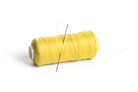 Yellow sewing thread spool with needle isolated on white background, closeup Stock Photos