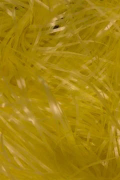 Yellow shredded plastic fake Easter grass background Stock Photos