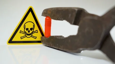 The yellow skull hazard sign infront of the rusty pliers Stock Footage 129453953