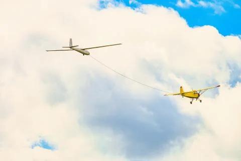 Yellow small light-engine sport plane flying in the cloudy sky Stock Photos