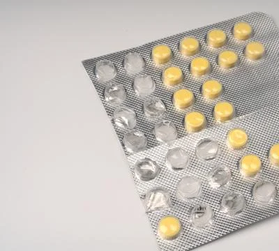 Yellow small tablets in a large package on a white background closeup. Foto stock