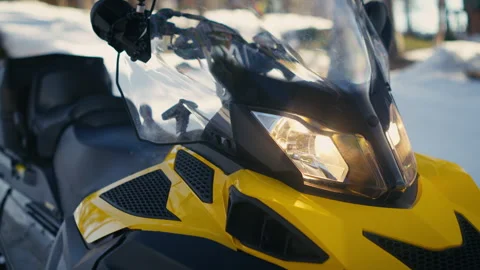Yellow Snowmobile with Headlights On in Spring Snow Stockbeeldmateriaal 339124063