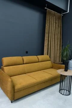 Yellow soft sofa in the interior against a gray wall Stock Photos
