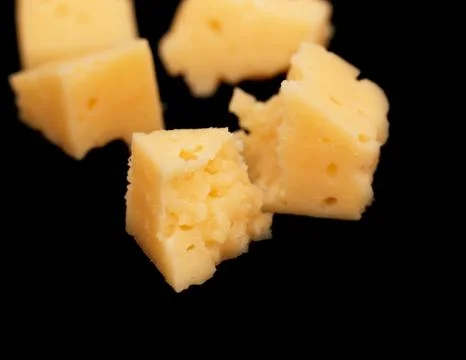 Yellow solid cheese pieces on a black background Foto stock