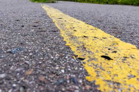 Yellow solid line, grunge single road marking on asphalt close up, background Stock Photos