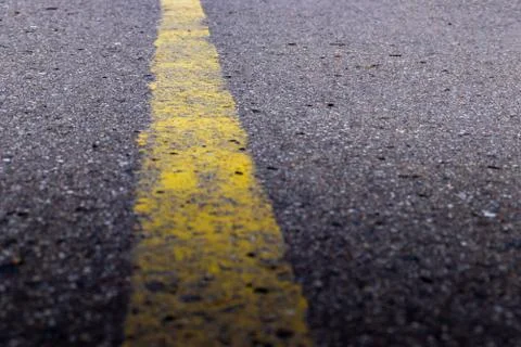Yellow solid line, grunge single road marking on asphalt, background with cop Stock Photos