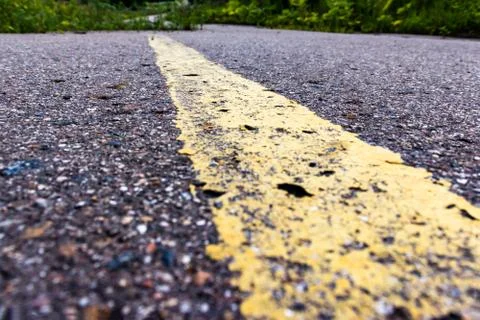 Yellow solid line, grunge single road marking on asphalt close up with rural  Stock Photos