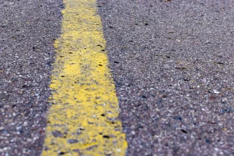 Yellow solid line, grunge single road marking on asphalt, background with cop Stock Photos