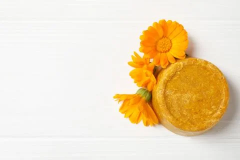 Yellow solid shampoo bar and flowers on white wooden table, flat lay. Space f 写真素材