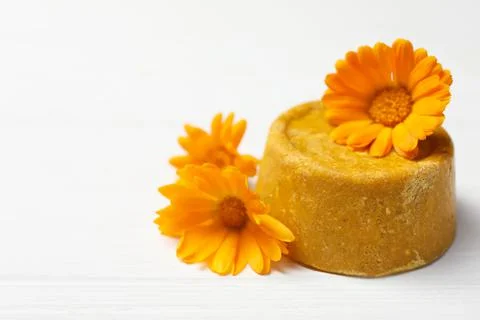 Yellow solid shampoo bar and flowers on white wooden table, closeup. Space fo Foto stock