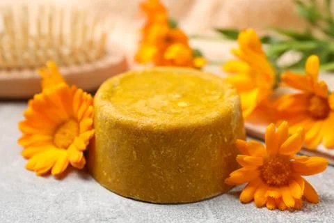 Yellow solid shampoo bar and flowers on light table, closeup. Hair care 写真素材