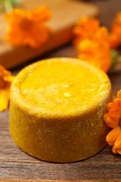 Yellow solid shampoo bar and flowers on wooden table, closeup. Hair care Foto stock