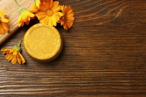 Yellow solid shampoo bar and flowers on wooden table, flat lay. Space for tex 写真素材