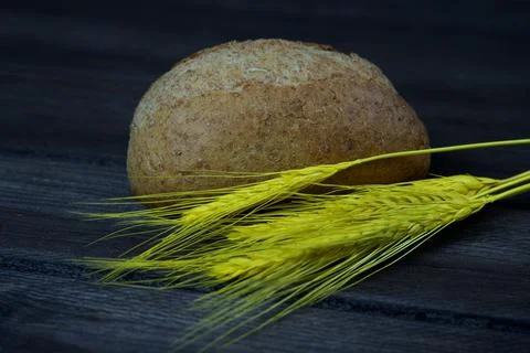Yellow spikelets and bread on black wooden table Stock Photos