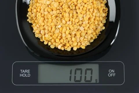 Yellow split lentils on kitchen scale Stock Photos
