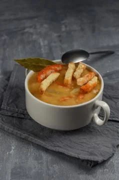 Yellow split pea soup in white plate with spoon on grey background. Foto stock