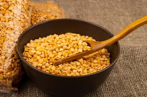 Yellow split peas in a cellophane bag and cereals in a ceramic bowl on a back Stock Photos