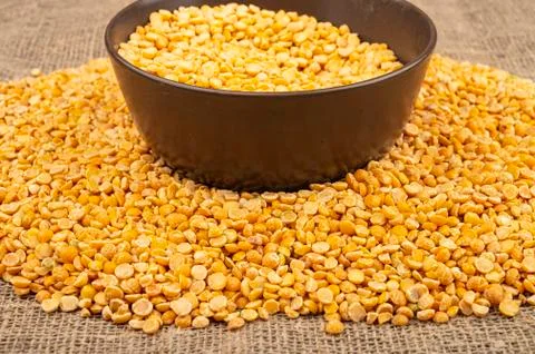 Yellow split peas in a ceramic bowl and grits scattered on a background of co Stock Photos
