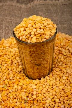 Yellow split peas in a cut glass and grits scattered on a background of coars Stock Photos