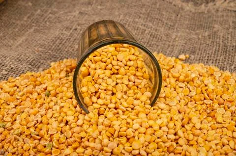Yellow split peas in a cut glass and grits scattered on a background of coars Stock Photos