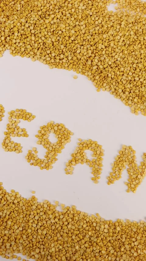 Yellow split peas form the letters VEGAN on a clean white surface. Stock Footage 309640879