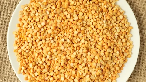 Yellow split peas rotating on a white plate Stock Footage 346180124