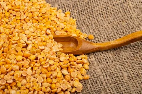 Yellow split peas scattered on a background of coarse-textured burlap. Tradit Stock Photos