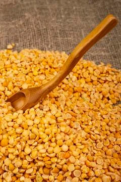 Yellow split peas scattered on a background of coarse-textured burlap. Tradit Stock Photos