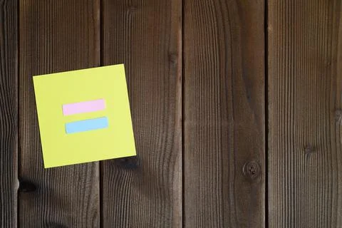 Yellow sticky note with equal sign cut out of paper on a wooden background. s Stock Photos