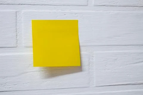 Yellow sticky note isolated on a background white brick wall Stock Photos