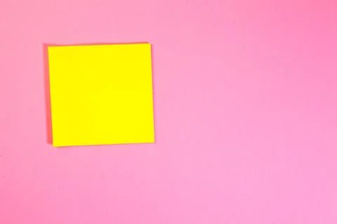 Yellow sticky note on pink background with copy space. Top view. Stock Photos