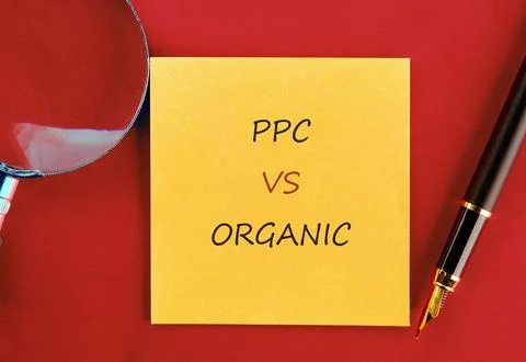 A yellow sticky note on a red background shows PPC VS ORGANIC in black and re Stock Photos