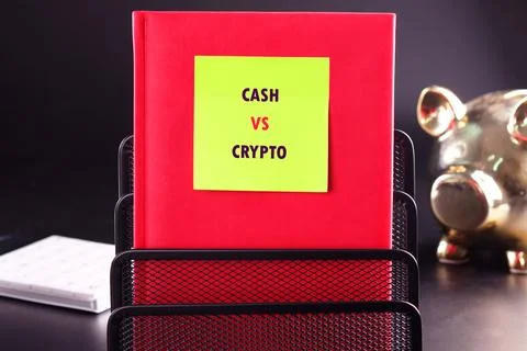 A yellow sticky note on a red binder displays CASH VS CRYPTO, symbolizing fin Stock Photos
